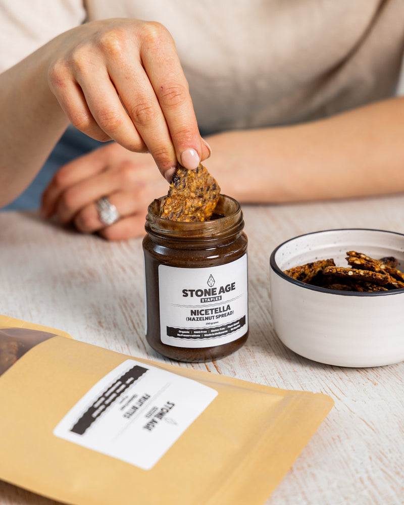 Close up shot of a jar of Nicetella or Hazelnut spread. Showing the front of the jar, including the label and dark brown, textured nut butter inside. Includes a black lid and displayed on a white background.