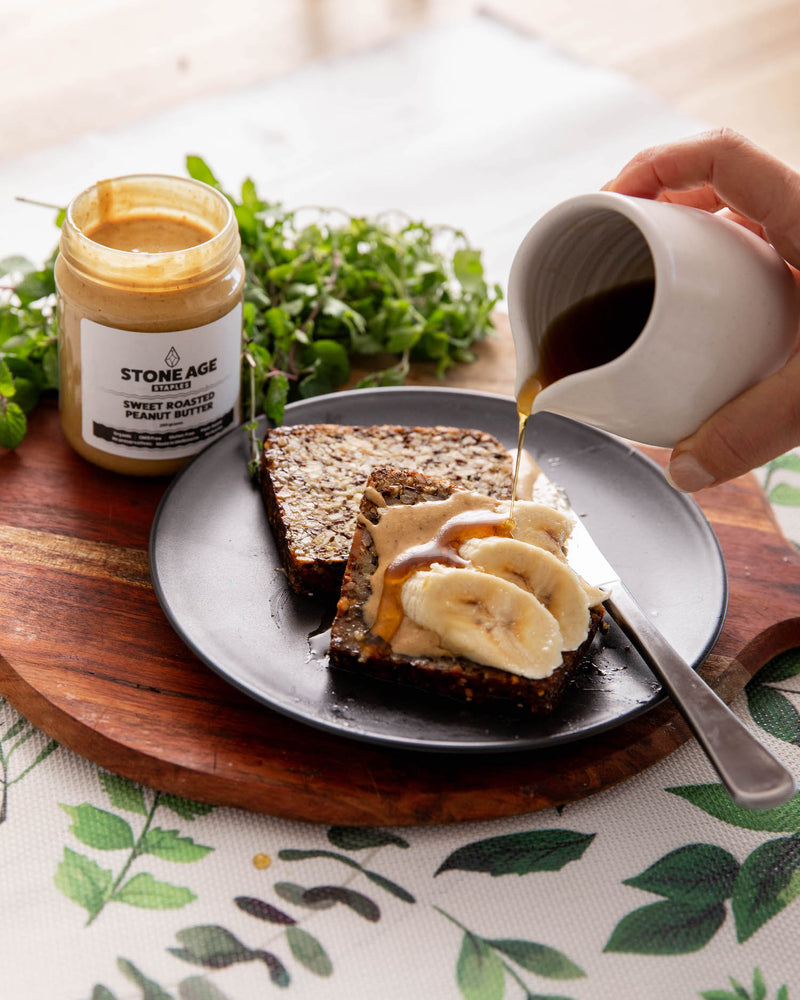 Close up shot of a jar of Sweet Roasted Peanut Butter. Showing the front of the jar, including the label and nut butter inside. Includes a black lid and displayed on a white background.